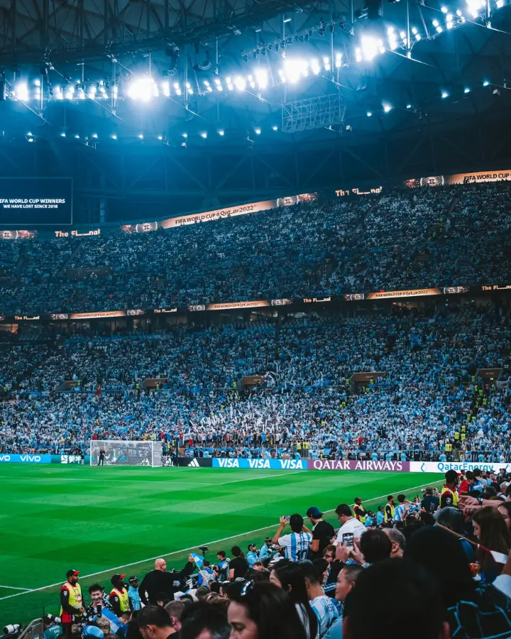 Estadio de fútbol lleno con hinchas argentinos y personal de seguridad junto al campo